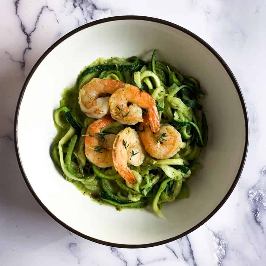 A bowl of AIP shrimp and zucchini pasta with green pesto sauce