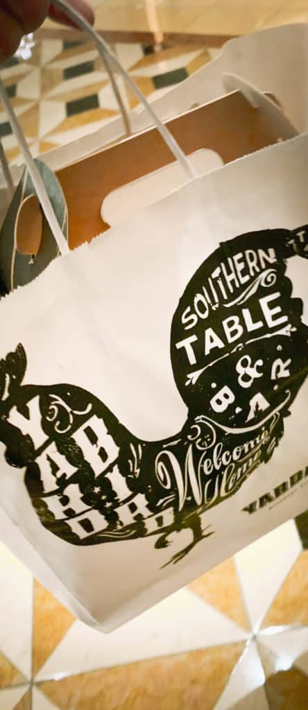 A white restaurant to go bag with a silhouette of a chicken. In the chicken, it says YardBird Southern Table and Bar