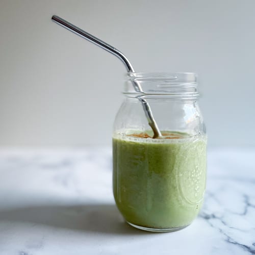 A green gluten free AIP smoothie in a jar with metal straw