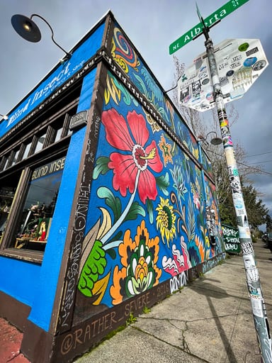 A mural of flowers on the side of a building with vivid blues, reds, and oranges